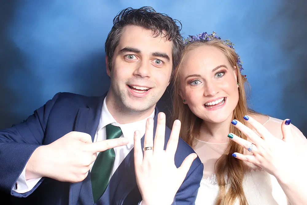 couple showing rings in photo booth