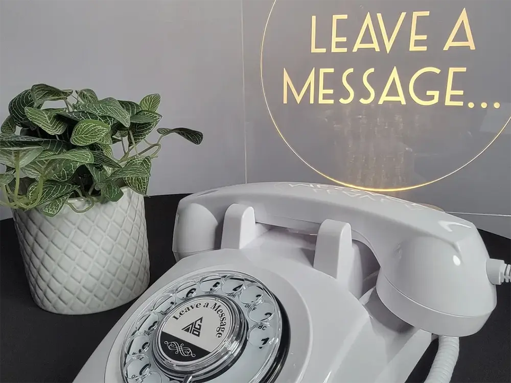 white vintage phone with Leave a Message glowing sign behind